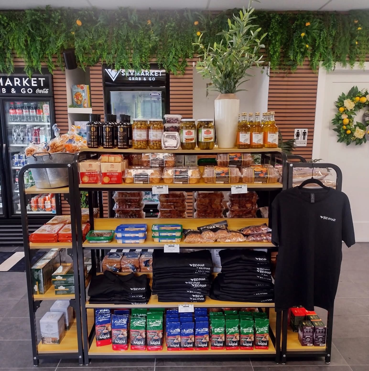 Sevmarket shelves with olives, cookies, coffee and SEVMAR tees